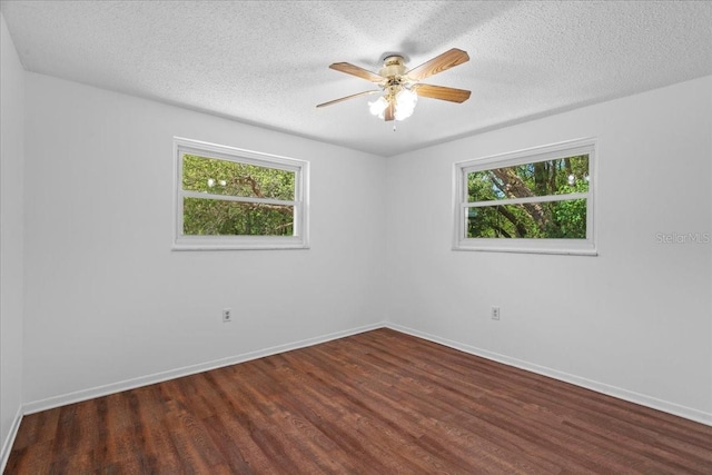 empty room featuring baseboards, ceiling fan, wood finished floors, and a wealth of natural light