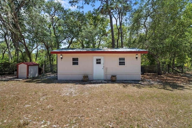 rear view of property with a storage shed and an outbuilding
