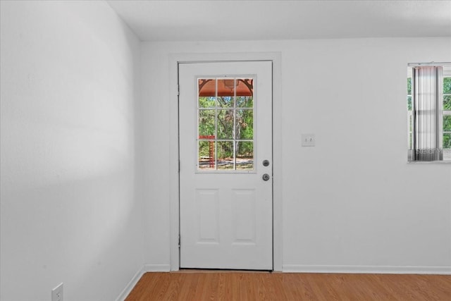 doorway with baseboards, light wood finished floors, and a wealth of natural light