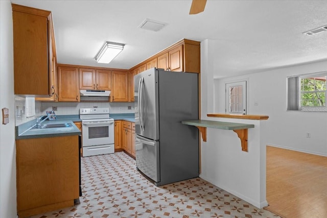 kitchen with freestanding refrigerator, under cabinet range hood, visible vents, and electric stove