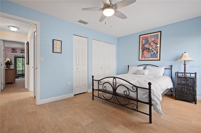 bedroom with visible vents, baseboards, light wood-style flooring, and two closets