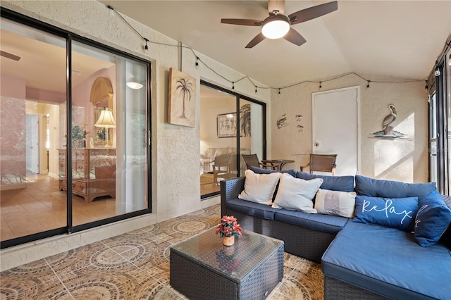 tiled living area with a textured wall, a ceiling fan, and vaulted ceiling