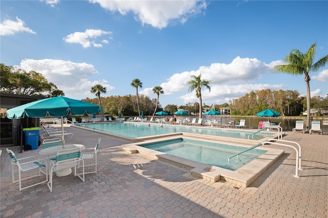 community pool featuring fence, a patio, and a hot tub