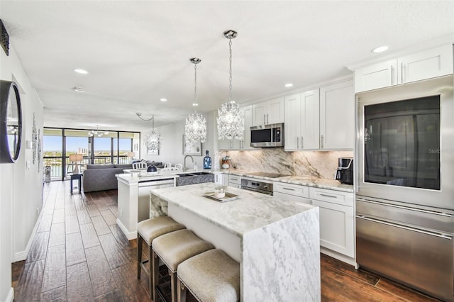 kitchen with decorative backsplash, a peninsula, recessed lighting, dark wood-type flooring, and appliances with stainless steel finishes