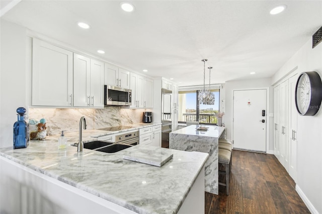 kitchen with a peninsula, a kitchen island, dark wood-style floors, stainless steel microwave, and backsplash