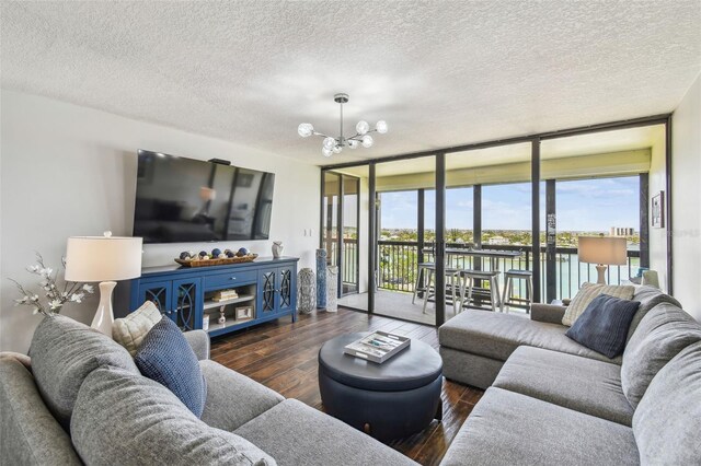 living room with expansive windows, a textured ceiling, a notable chandelier, and hardwood / wood-style flooring
