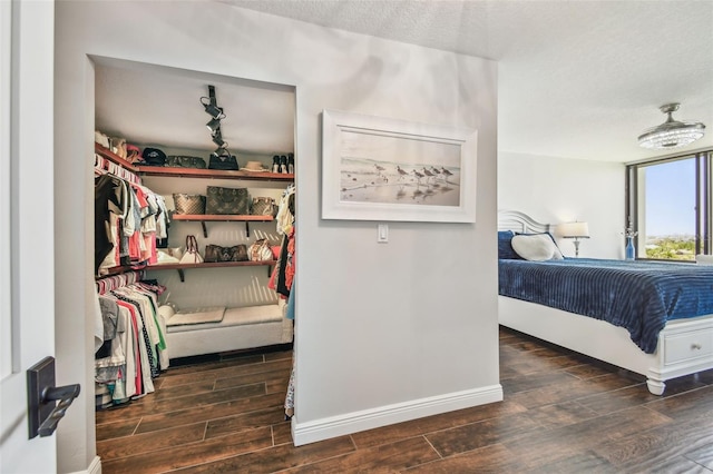 bedroom featuring baseboards, a textured ceiling, and wood finished floors