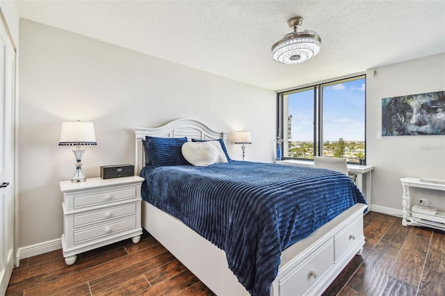 bedroom featuring baseboards, a textured ceiling, and dark wood finished floors