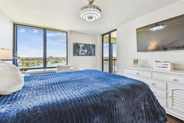 bedroom with a wall of windows, multiple windows, a textured ceiling, and access to exterior
