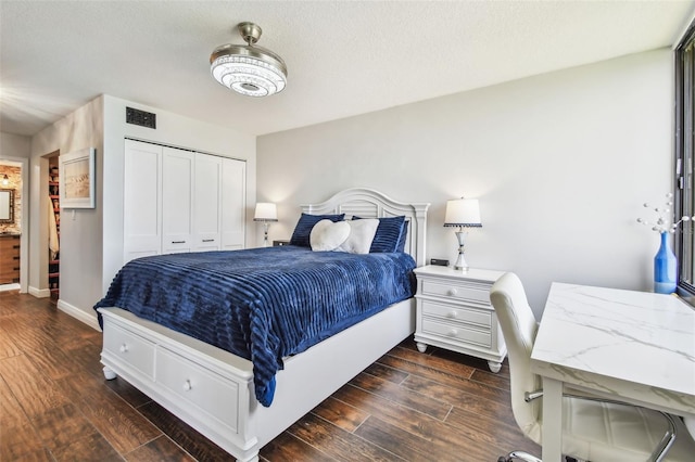 bedroom with baseboards, visible vents, dark wood finished floors, and a closet