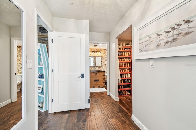 hall featuring baseboards, a textured ceiling, and hardwood / wood-style floors