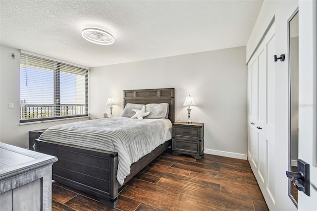 bedroom featuring a textured ceiling, baseboards, dark wood finished floors, and a closet