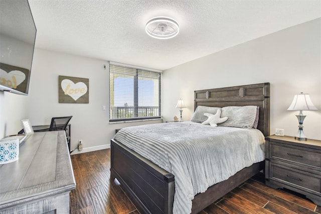 bedroom featuring baseboards, dark wood-style flooring, and a textured ceiling
