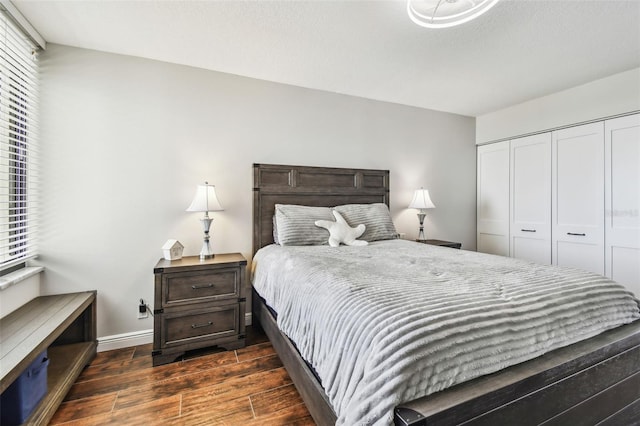 bedroom featuring baseboards, dark wood-style floors, and a closet