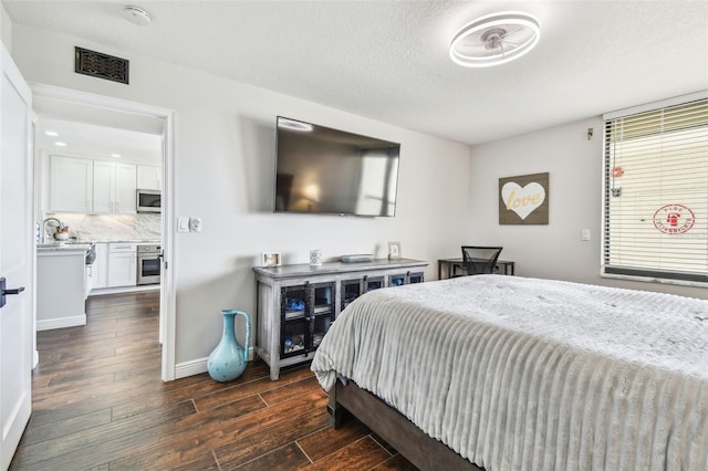 bedroom with dark wood-type flooring, a textured ceiling, baseboards, and a sink
