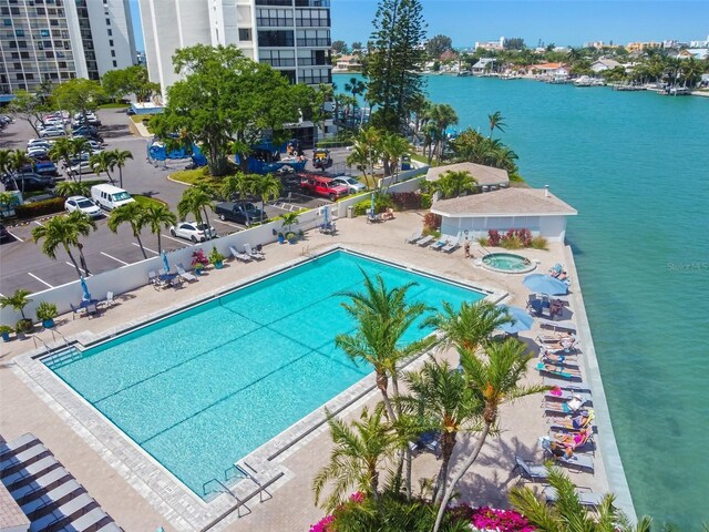 community pool featuring a water view, fence, and a patio area