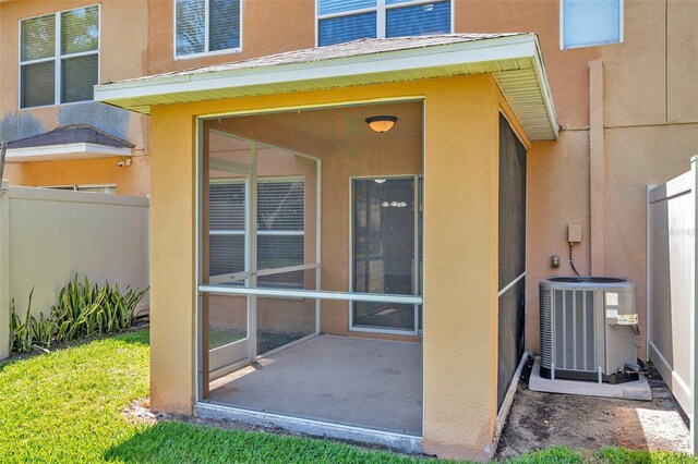 entrance to property featuring stucco siding, central air condition unit, fence, and a patio