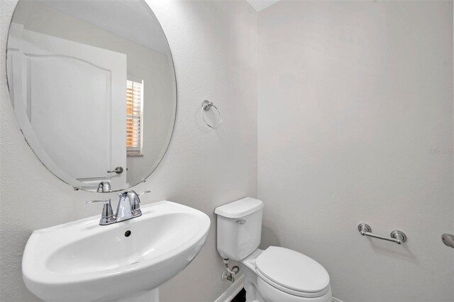 bathroom featuring baseboards, a sink, and toilet