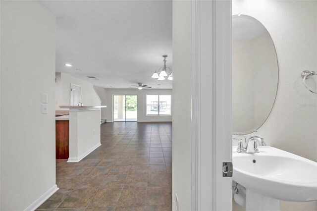 bathroom featuring baseboards, a sink, ceiling fan with notable chandelier, and recessed lighting