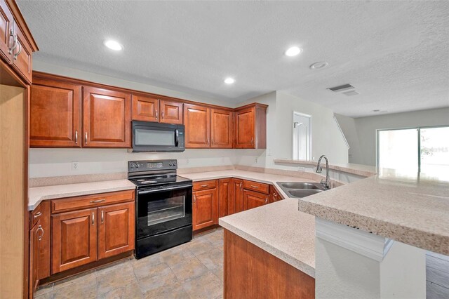 kitchen with brown cabinets, a sink, light countertops, black appliances, and a peninsula