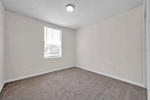 carpeted empty room featuring baseboards and a textured ceiling