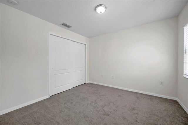 unfurnished bedroom with baseboards, visible vents, carpet, and a closet