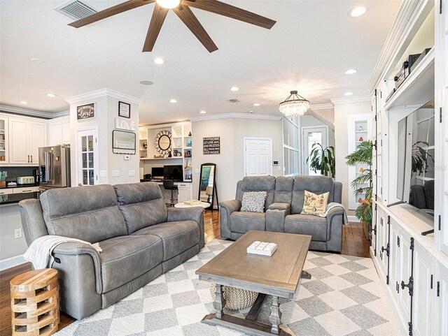 living room featuring ornamental molding, ceiling fan with notable chandelier, recessed lighting, and visible vents
