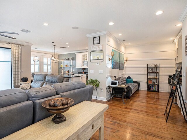 living room with crown molding, recessed lighting, visible vents, and wood finished floors