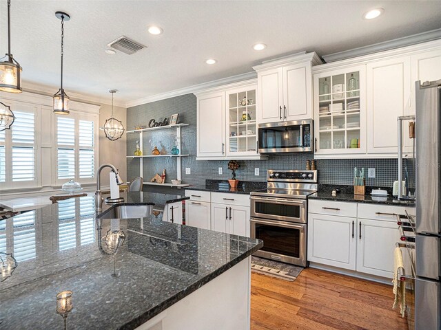kitchen with white cabinets, a sink, stainless steel appliances, tasteful backsplash, and ornamental molding