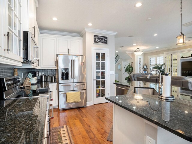 kitchen with ornamental molding, white cabinets, a sink, appliances with stainless steel finishes, and backsplash