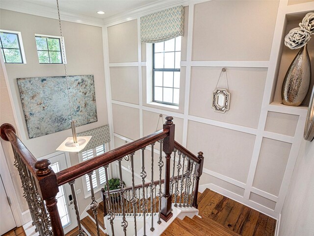 staircase with ornamental molding, recessed lighting, and wood finished floors