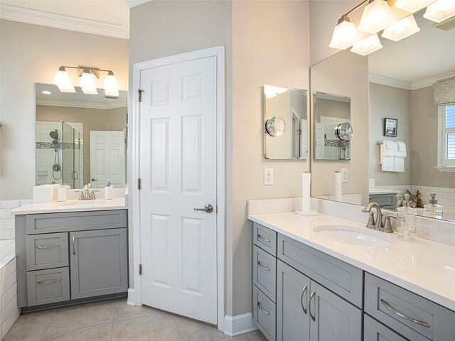 bathroom featuring tile patterned flooring, a sink, crown molding, and a stall shower