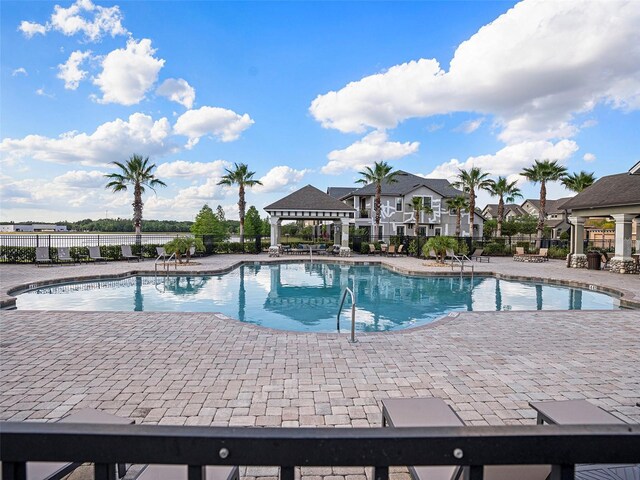 pool with a patio area and fence
