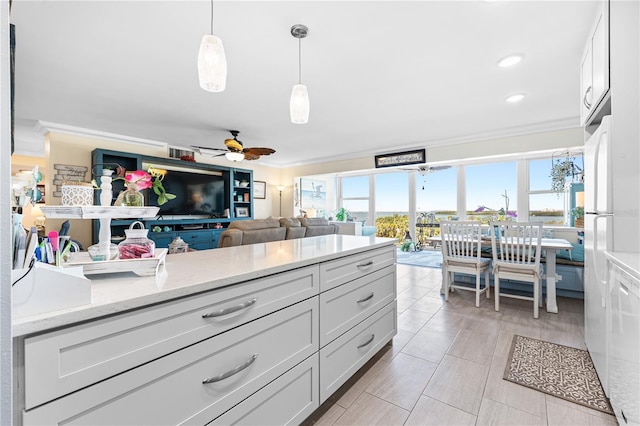kitchen featuring ceiling fan, decorative light fixtures, crown molding, light stone counters, and open floor plan