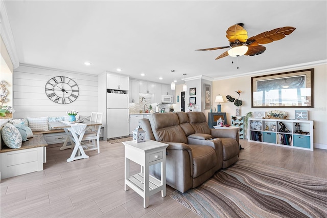 living room featuring crown molding, a ceiling fan, recessed lighting, and light wood-style flooring