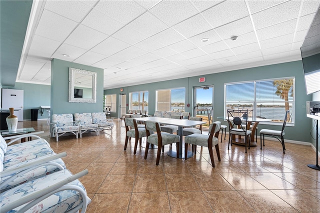 tiled dining space with baseboards and a paneled ceiling