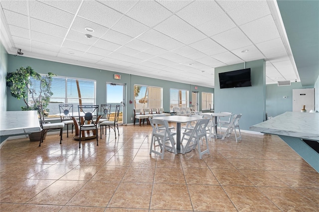 dining area with light tile patterned floors, baseboards, and a drop ceiling