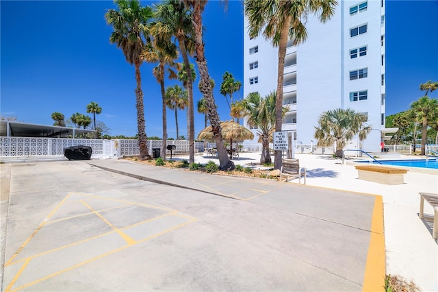 view of property featuring a community pool and uncovered parking