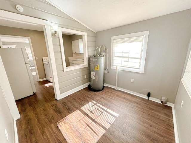 unfurnished room with washer / dryer, wood finished floors, lofted ceiling, baseboards, and water heater