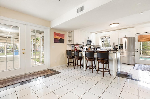 kitchen with french doors, visible vents, a peninsula, stainless steel appliances, and white cabinets
