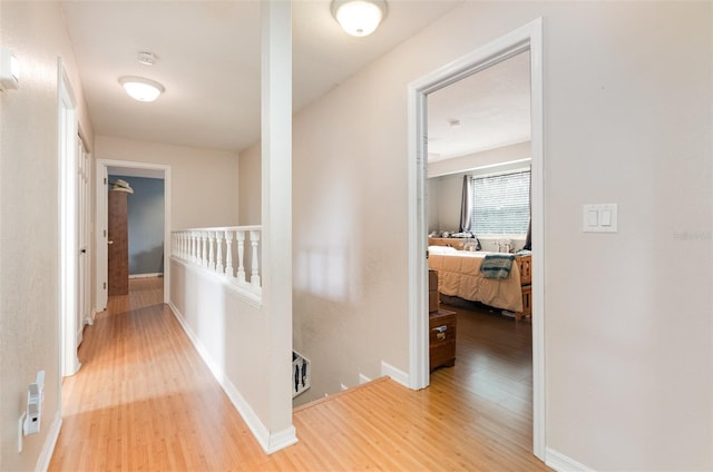hallway with wood finished floors, an upstairs landing, and baseboards