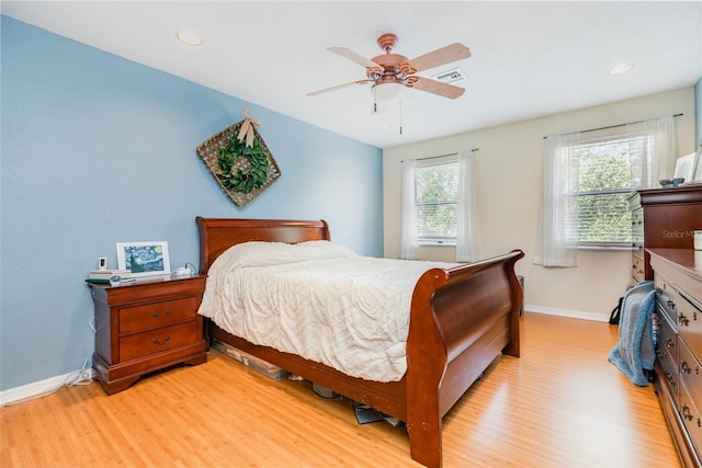 bedroom with light wood finished floors, visible vents, baseboards, and a ceiling fan
