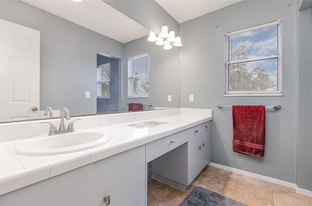 bathroom with baseboards, a healthy amount of sunlight, and vanity