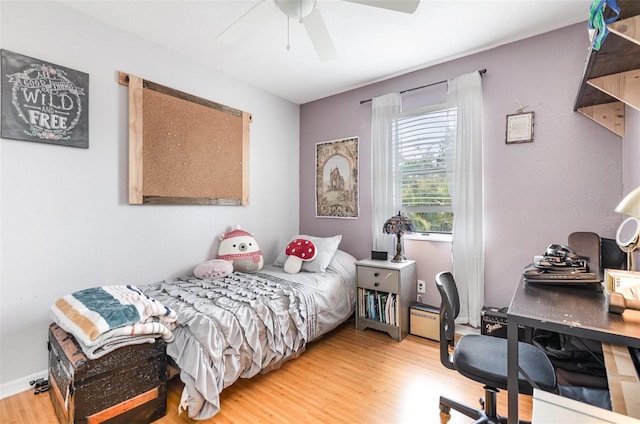 bedroom with ceiling fan, light wood-type flooring, and a baseboard heating unit