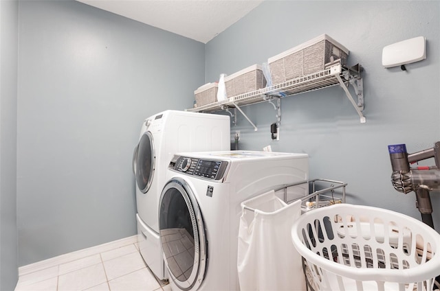 laundry area featuring baseboards, tile patterned floors, laundry area, and independent washer and dryer