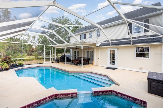 view of swimming pool with french doors, a pool with connected hot tub, ceiling fan, a patio area, and glass enclosure