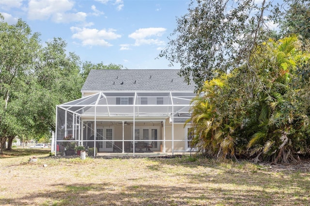 rear view of property featuring french doors, a ceiling fan, a shingled roof, a patio area, and a lanai