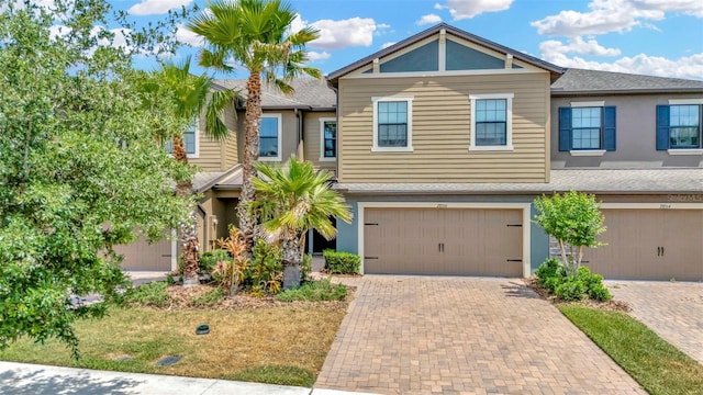 view of front of home with an attached garage, decorative driveway, stucco siding, and a shingled roof