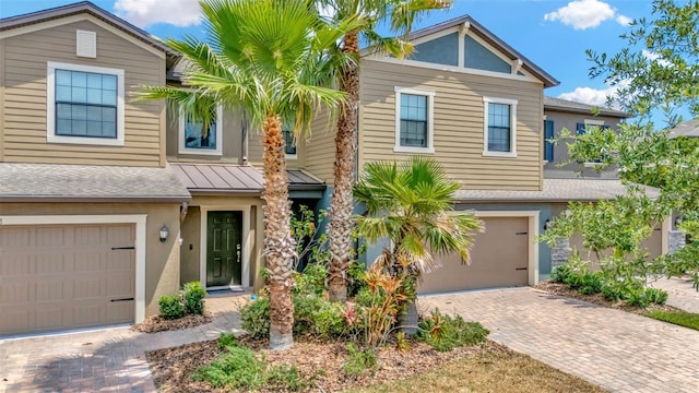 view of front of property featuring stucco siding, decorative driveway, a shingled roof, and a garage