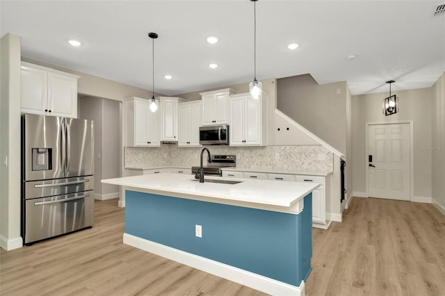 kitchen featuring appliances with stainless steel finishes, a sink, light wood-style floors, light countertops, and decorative backsplash